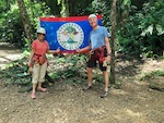 Photo from Susan's Story, Susan and Hugh in front of the flag of the country of Belize